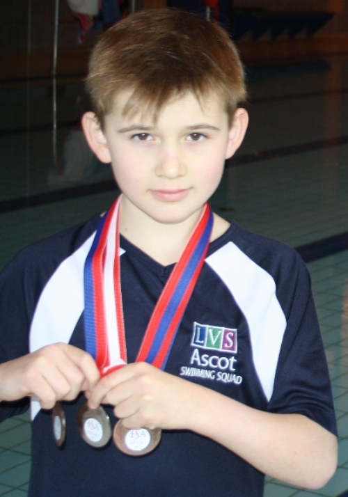 Archie Gardiner with his three medals at the LVS Ascot school swimming pool 